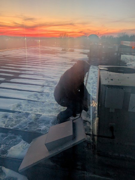 Air Heroes technician servicing rooftop equipment in winter